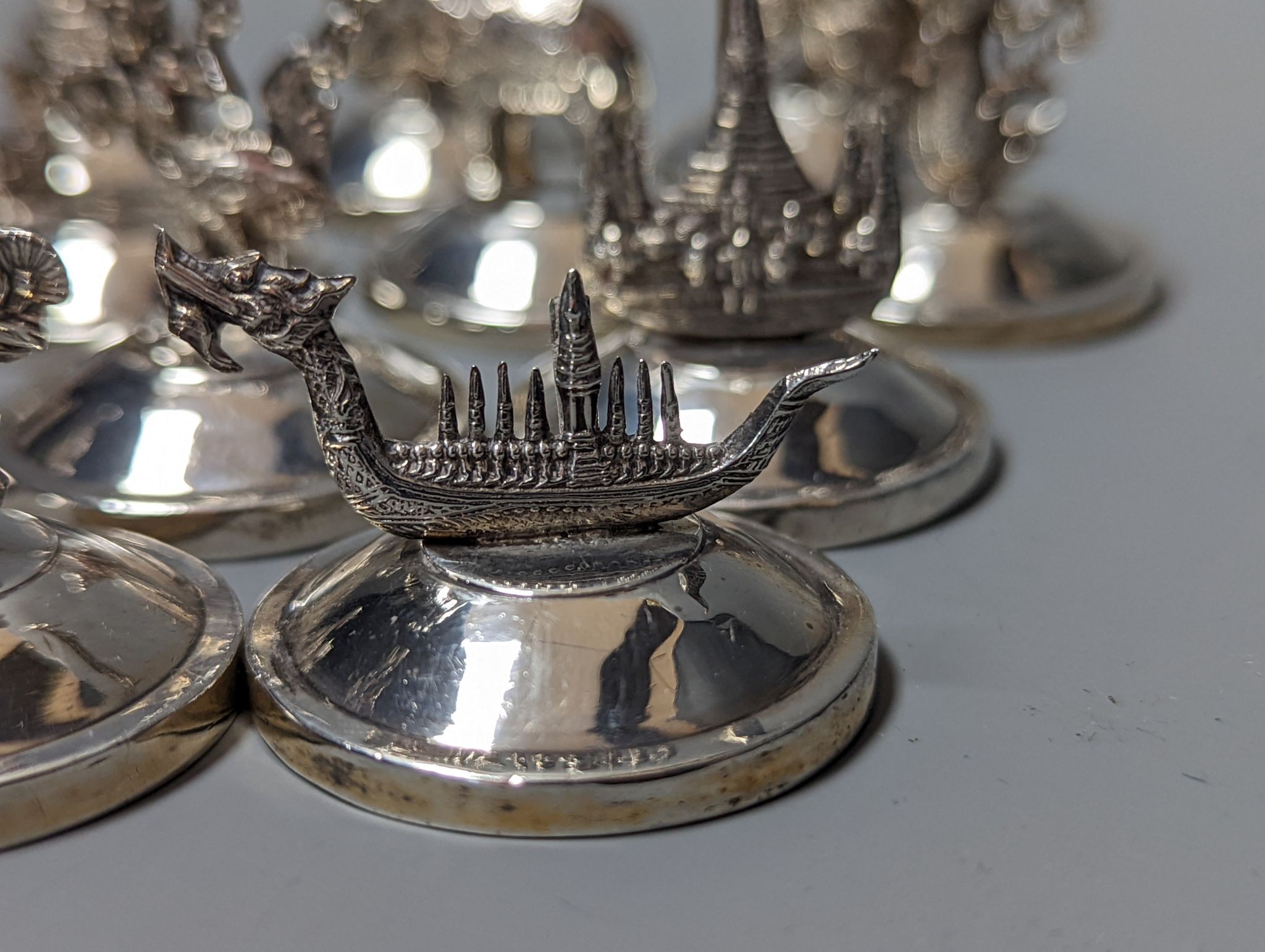 Sixteen assorted Siamese sterling mounted menu holders, modelled with figures, elephant, etc.